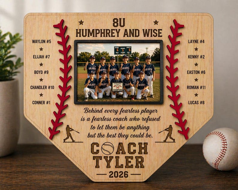 May include: A wooden baseball home plate-shaped plaque with a team photo. The plaque features the text "8U Humphrey and Wise", player names, and "Coach Tyler 2026". Red stitching and baseball silhouettes decorate the edges. A baseball sits to the right.