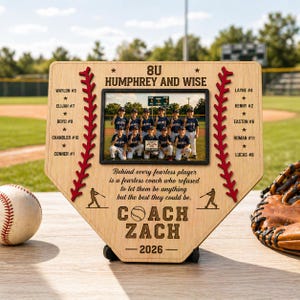 May include: A wooden baseball home plate-shaped plaque with a photo of a youth baseball team. The plaque has red stitching and text that reads "COACH ZACH 2026". A baseball and glove are next to the plaque.