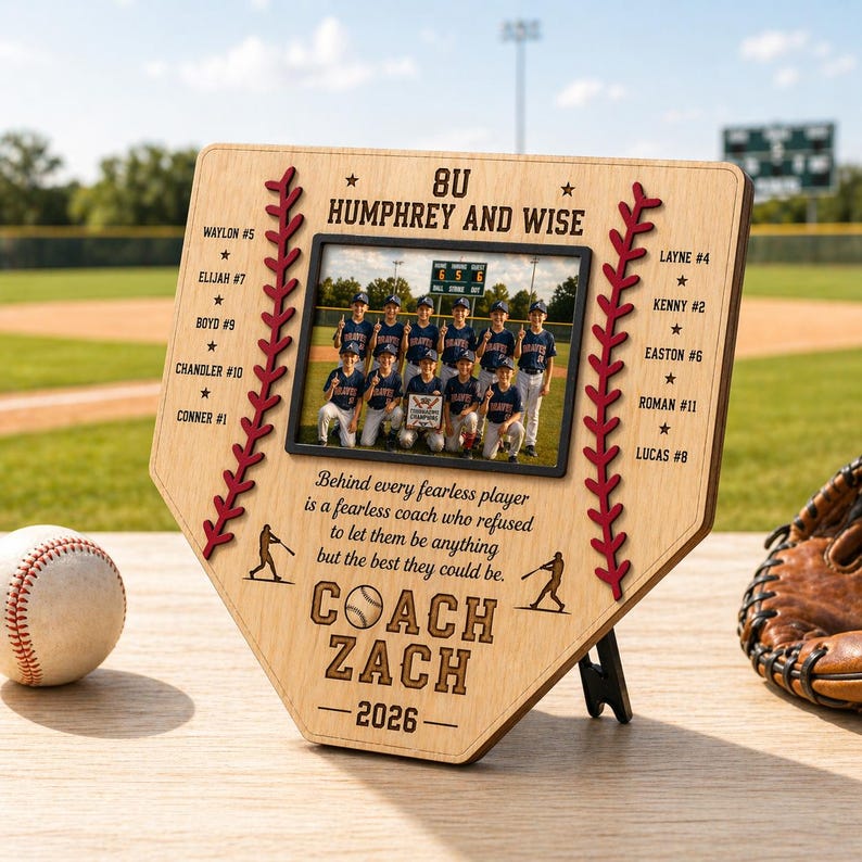 May include: A wooden baseball-themed plaque with a team photo, names, and the text "COACH ZACH - 2026." The plaque features a baseball and stitching design, with a baseball and glove in the foreground.