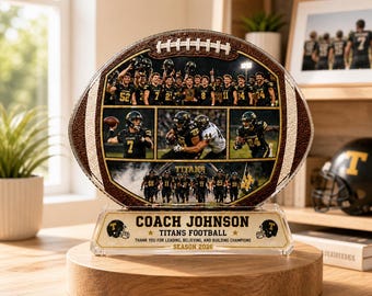 May include: A football-shaped decorative piece featuring team photos and the text "COACH JOHNSON TITANS FOOTBALL SEASON 2026". The piece is brown and gold, mounted on a wooden base, and includes a clear acrylic stand.