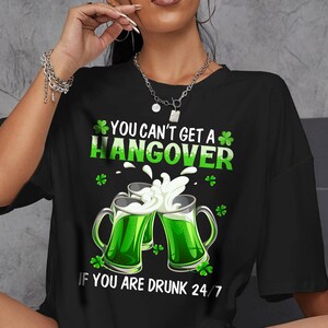 May include: Black t-shirt with a green shamrock design and the text "You can't get a hangover if you are drunk 24/7".
