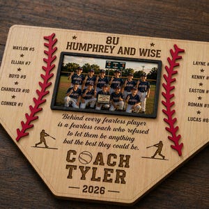 May include: A wooden baseball-shaped plaque with a team photo, player names, and the text "8U Humphrey and Wise." The plaque includes red stitching, baseball player silhouettes, and the coach's name, "Coach Tyler," with the year 2026.