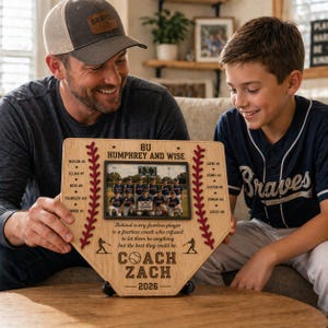 May include: A wooden baseball home plate-shaped plaque with a team photo. The plaque features the text "8U Humphrey and Wise", player names, and "Coach Zach - 2026". Decorative red stitching and a quote are also included.