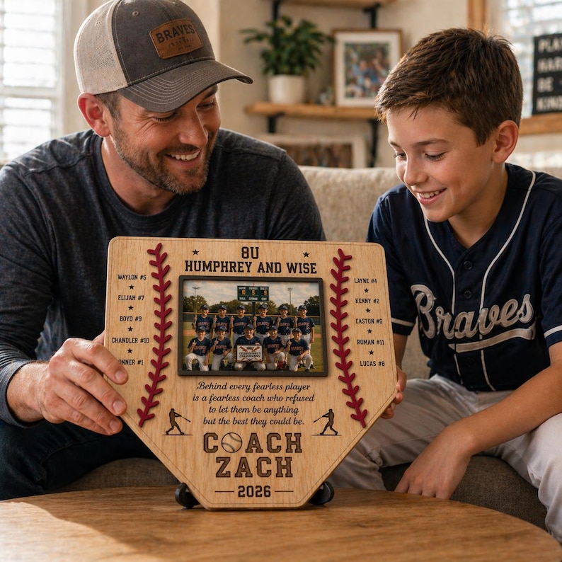 May include: A wooden baseball home plate-shaped plaque with a team photo. The plaque features the text "8U Humphrey and Wise", player names, and "Coach Zach - 2026". Decorative red stitching and a quote are also included.