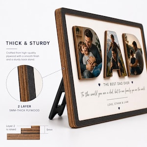 May include: A wooden photo frame with the word "DAD" in raised letters, each letter containing a family photo. The frame has a black border and a white background with text that reads "THE BEST DAD EVER". The frame is supported by a black stand.