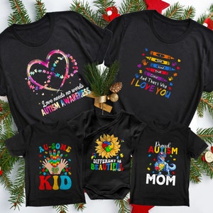 May include: Set of four black t-shirts with autism awareness designs. The shirts feature a heart made of jigsaw pieces, a sunflower with a jigsaw piece in the centre, a handprint with jigsaw pieces, and a dinosaur holding a jigsaw piece. The shirts also include the text "Love needs no words Autism Awareness", "Au-some Kid", "Different is Beautiful", and "Proud Autism Mom".