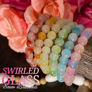 Puede incluir: Pulseras de cristal veteado multicolor con cuentas de 8 mm. Las pulseras muestran un arcoíris de colores. El texto "SWIRLED GLASS 8mm Bracelets" es visible en la imagen.