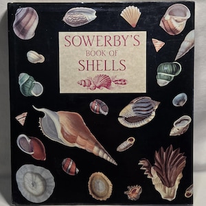 May include: A hardcover book titled Sowerby's Book of Shells with a black cover featuring various illustrations of seashells in shades of brown, tan, white, and green. The central rectangular label displays the title in red serif lettering.