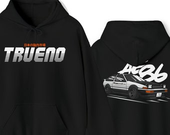 Può includere: Felpa con cappuccio nera con una grafica bianca di un'auto e il testo "TRUENO" e "日本の国内市場" sul davanti e una grafica bianca di un'auto con il testo "AE86" sul retro.