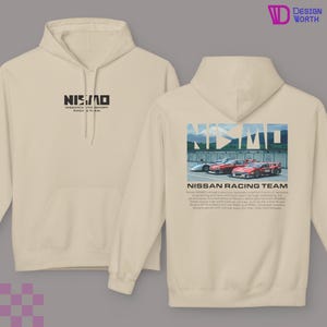 May include: Cream-colored hoodie with the text "NISMO" on the front and a graphic of race cars with the text "NISSAN RACING TEAM" on the back. The hoodie has a hood and a front pocket.