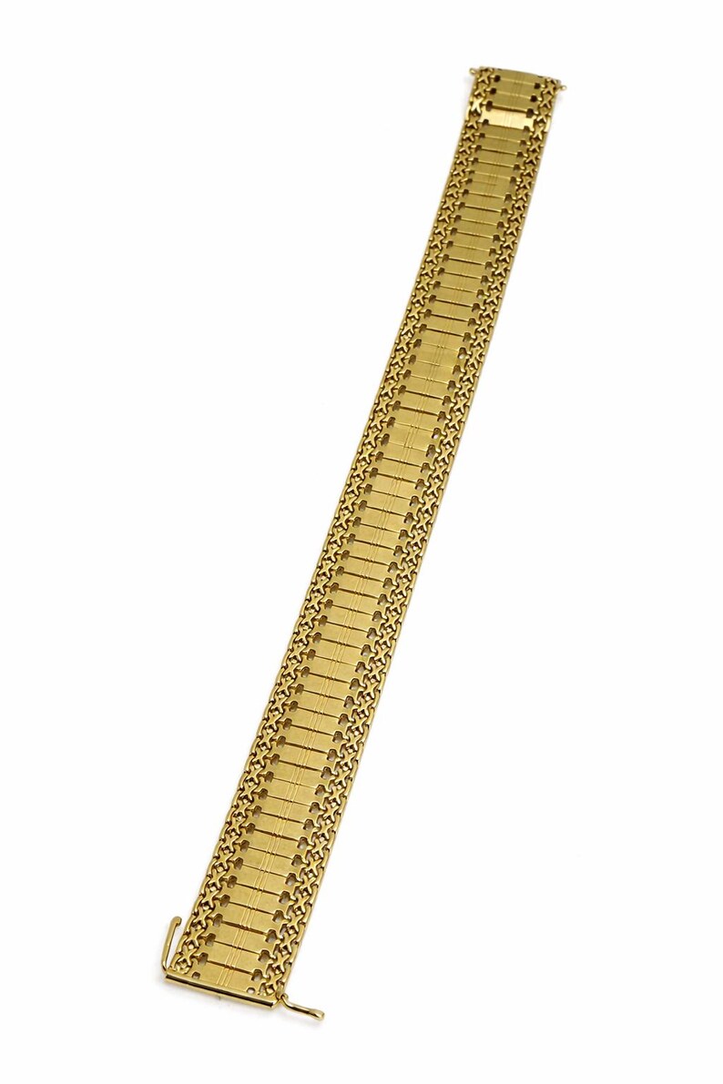 May include: A gold-toned watch band with a rectangular link design. The band is made of metal and features a clasp closure. The watch band is shown against a white background.