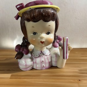 Vaso da fiori in porcellana per bambina della scuola Napco, vestito a quadretti rosa, capelli castani con trecce e nastri rosa