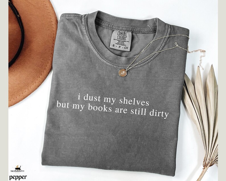 May include: A gray t-shirt with the text "i dust my shelves but my books are still dirty" printed in white.