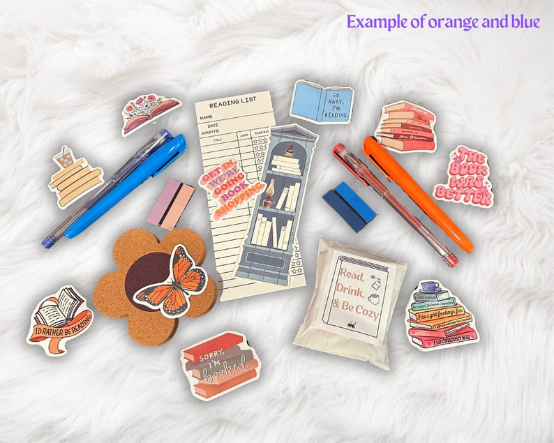 Op de afbeelding: Een verzameling boek-thema stickers met zinnen zoals "Get in, we're going book shopping", "The book was better", en "Read, Drink, & Be Cozy". De stickers zijn op een witte achtergrond met een kurken onderzetter, pennen en een leeslijst.
