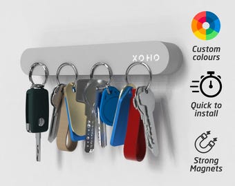 May include: A gray magnetic key holder with the brand name "XOHO" printed on it. Several keys with colorful keychains are attached. The image also includes icons and text that say "Custom colours", "Quick to install", and "Strong Magnets".