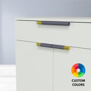 May include: White cabinet with two drawers and two doors, featuring dark gray cylindrical handles with gold-colored ends. The image includes a color wheel with the text "CUSTOM COLORS".