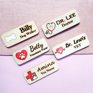 May include: Five wooden name tags with different titles and icons. The tags read "Billy Dog Walker", "Betty Veterinary Nurse", "Amina Vet Nurse", "Dr. Lee Doctor", and "Dr. Lewis VET".