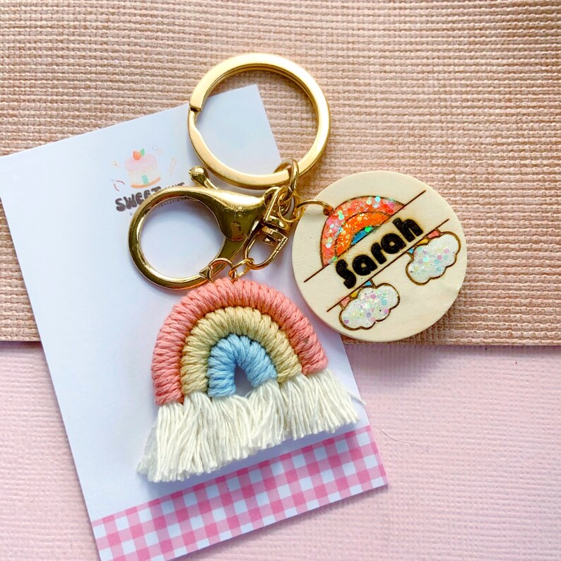 May include: A rainbow-colored crocheted keychain with white tassels and a wooden tag with the name "Sarah" and a rainbow with glitter.