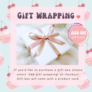May include: A white gift box with a pink ribbon tied around it. The ribbon has gold lettering that says "Just for you". The box is sitting on a white surface. The image has a pink background with a text overlay that says "Gift Wrapping" and "Add On Option".