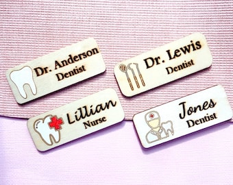 May include: Four wooden name tags with different designs and text. The first tag has a tooth and the text "Dr. Anderson Dentist". The second tag has dental tools and the text "Dr. Lewis Dentist". The third tag has a tooth with a red cross and the text "Lillian Nurse". The fourth tag has a cartoon dentist and the text "Jones Dentist".