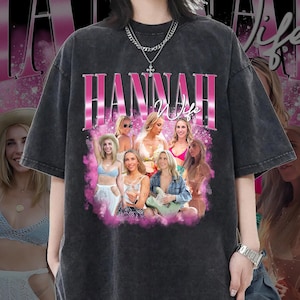 Puede incluir: Camiseta negra con un estampado gráfico rosa de la palabra "HANNAH" con la palabra "Wife" debajo. El gráfico también incluye un collage de mujeres en una nube rosa.