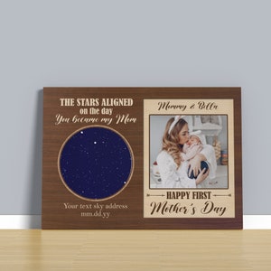 May include: A wooden plaque with a star chart and a photo of a mother and baby. The text reads "The stars aligned on the day you became my Mom" and "Happy First Mother's Day".