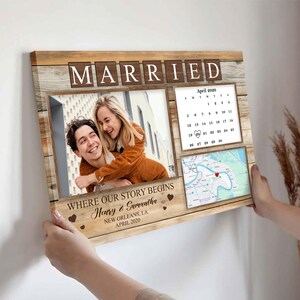 May include: A wooden framed canvas print with the word "MARRIED" in block letters. It features a photo of a couple, a calendar, and a map. The text "WHERE OUR STORY BEGINS" and names are also visible. The date is April 2020.