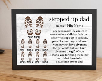 May include: A white wooden sign with brown cutout footprints and the text "stepped up dad" and "name | His Name". The text continues with a definition of what a stepped up dad is. The sign is framed in black.
