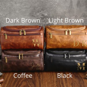 May include: Four toiletry bags in different colors: dark brown, light brown, coffee, and black. Each bag has a zipper closure and a personalized monogram.