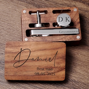 May include: A wooden box with a personalised inscription reading "Daniel Best man 08-05-2025". The box contains a tie clip engraved with "Groomsmen" and a cufflink set with the initials "D|K".