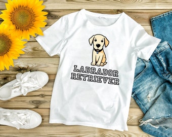 May include: White t-shirt with a cartoon Labrador Retriever puppy wearing a collar and the text "Labrador Retriever" printed in black.