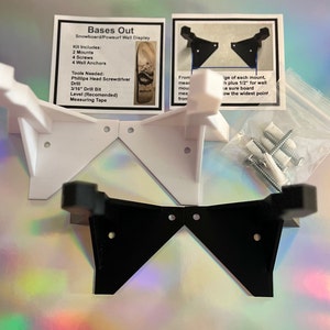 May include: Two wall mounts for displaying a snowboard or surfboard. The mounts are made of white and black plastic and are shown against a rainbow iridescent background. The mounts are designed to be attached to a wall and have a triangular shape. The kit includes screws and wall anchors.