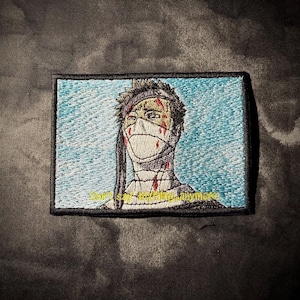 May include: A rectangular embroidered patch featuring a character with a bandaged face and head, marked with red blood-like streaks against a light blue background. The yellow text at the bottom reads, "Don't say anything anymore."