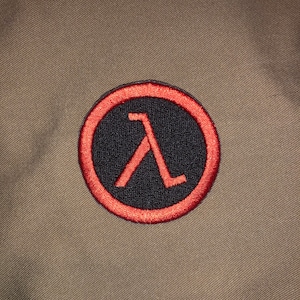 May include: A red and black embroidered patch with the Lambda symbol, a stylized letter "A", inside a circle.