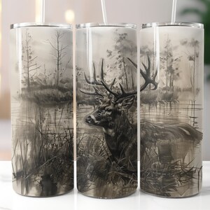 May include: A stainless steel tumbler with a black and white illustration of a deer in a forest setting. The deer is standing in a body of water with trees and foliage in the background.