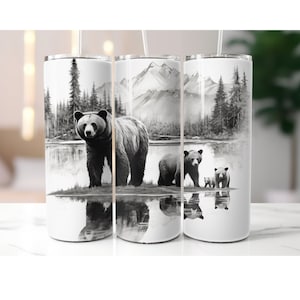 May include: Three stainless steel tumblers with a black and white illustration of a bear and two cubs standing in a lake with mountains and trees in the background.