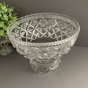 May include: A large, clear glass bowl with a cut-glass design. The bowl has a wide, round base and a flared rim. It is perfect for serving fruit, salads, or other dishes.