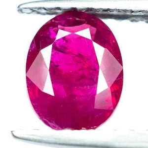 Peut inclure: Une pierre précieuse de rubis ovale de couleur rose vif tenue dans des pinces.