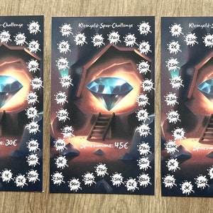Könnte beinhalten: Drei Karten mit einem Edelstein-Design. Jede Karte zeigt einen großen, leuchtenden blauen Diamanten in einer Höhlenumgebung, umgeben von weißen Spritzern und Text. Die Karten zeigen unterschiedliche Sparbeträge.
