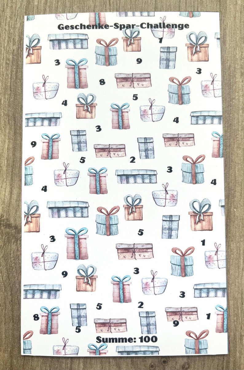 May include: A white sheet of paper with a pattern of brown, blue, and pink gift boxes. Each box has a number on it. The text "Geschenke-Spar-Challenge" and "Summe: 100" is at the top and bottom of the sheet.