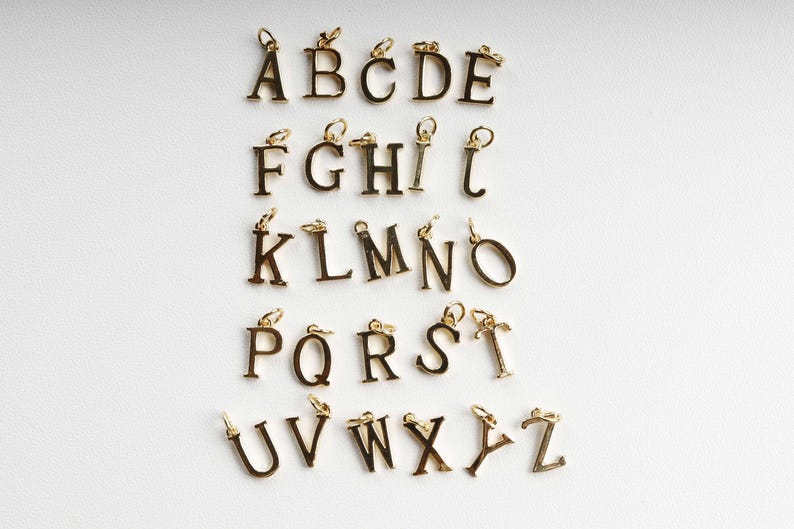 May include: Gold-coloured alphabet charms, each with a small loop for attaching to a chain or bracelet. The letters A to Z are displayed against a white background. These charms are ideal for personalised jewellery.