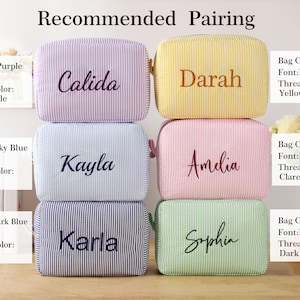 K&ouml;nnte beinhalten: Sechs personalisierte Kosmetiktaschen in verschiedenen Farben, darunter Lila, Gelb, Himmelblau, Rosa, Dunkelblau und Gr&uuml;n. Jede Tasche hat einen Namen in einer Kontrastfarbe gestickt. Der Text "Recommended Pairing" steht oben.