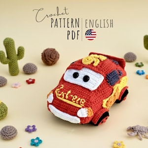 Può includere: Un'auto rossa all'uncinetto con dettagli bianchi e la scritta "Ext-ere" in giallo. L'immagine include cactus, fiori e altri elementi decorativi all'uncinetto. Il testo "Crochet Pattern English PDF" è in alto.
