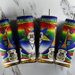 Puede incluir: Cuatro vasos coloridos con un fondo de arcoíris y una estrella de cinco puntas con las palabras "Orden de la Estrella del Este" en una pancarta en la parte inferior. La estrella tiene una brújula y una escuadra en el centro y las letras "O.E.S." en los puntos.