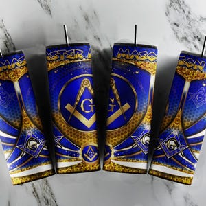 Può includere: Quattro bicchieri massonici blu e oro con cannucce nere. Ogni bicchiere presenta il simbolo massonico della squadra e del compasso, la lettera "G" e le parole "MASTER MASON". Il design include accenti glitterati dorati e uno sfondo stellato.