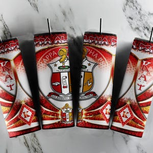 May include: Four red and gold tumblers featuring a Kappa Alpha Psi fraternity crest and the letters "KAPPA" in a heart shape. The tumblers have a white background with a red and gold design.