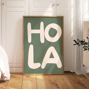 Op de afbeelding: Een groene geframed poster met witte tekst die "HO LA" zegt in een speels, afgerond lettertype.