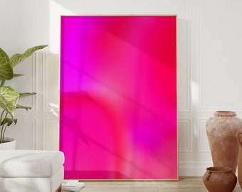 Puede incluir: Una impresión de arte abstracto enmarcada con un degradado de colores rosa y magenta. La impresión está colgada en una pared blanca con un suelo de madera.