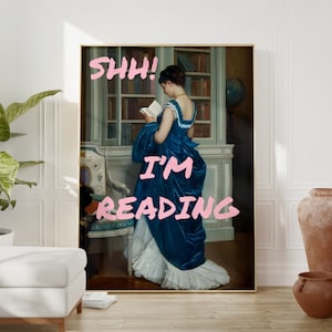May include: A painting of a woman in a blue dress reading a book in a library. The text "Shh! I'm reading" is written in pink letters on the painting.