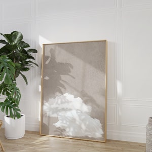 Könnte beinhalten: Ein gerahmter abstrakter Druck mit beigefarbenem Hintergrund und einer weißen, wolkenartigen Form. Der Druck ist in einem goldenen Rahmen und hängt an einer weißen Wand.